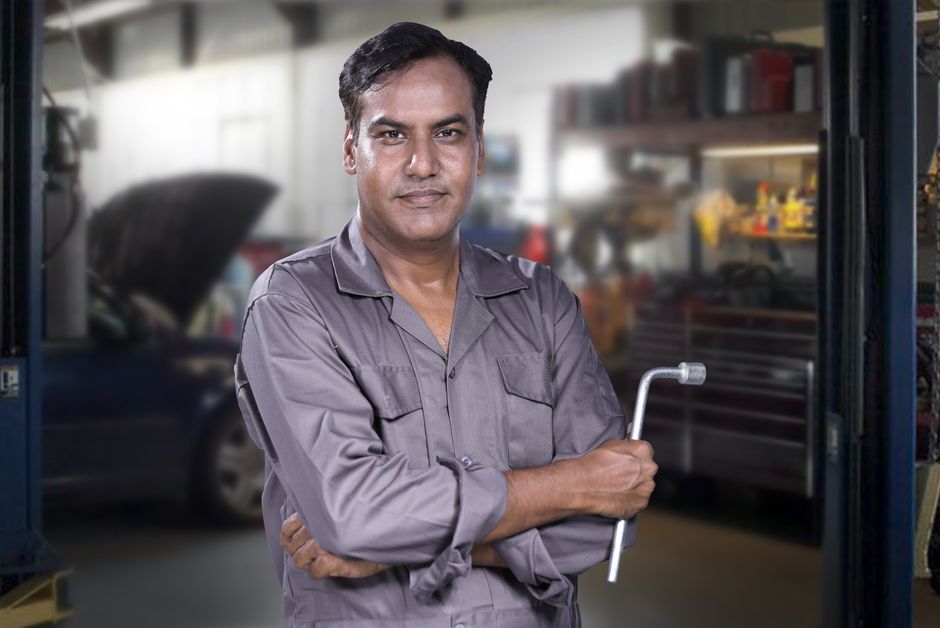 Smiling auto mechanic standing in a clean garage