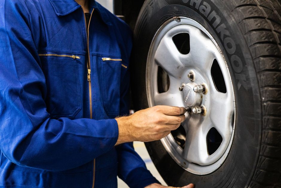 Mechanic carefully mounting a car wheel in the shop